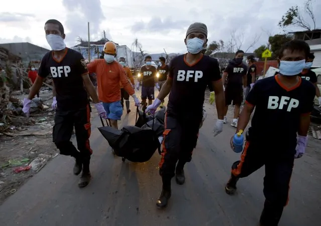 Firemen carry the newly recovered body of a victim of Typhoon Haiyan in Tacloban, central Philippines, Wednesday, November 13, 2013. (Photo by Dita Alangkara/AP Photo)