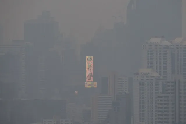 A large illuminated advertisement on the side of a building is pictured amid high levels of air pollution in Bangkok on October 18, 2023. Air quality in the Thai capital could reach above a safe limit, the kingdom's pollution control agency warned on October 18, as the crop-burning season approaches. (Photo by Alex Ogle/AFP Photo)