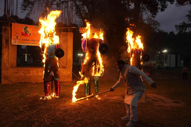 A man burns effigies of demon king Ravana, his  brother Kumbhakarna and his son Meghanada marking the end of Dussehra festival in Srinagar, Indian controlled Kashmir, Tuesday, October 24, 2023. Dussehra commemorates the triumph of Hindu god Rama over the demon king Ravana, marking the victory of good over evil. (Photo by Mukhtar Khan/AP Photo)