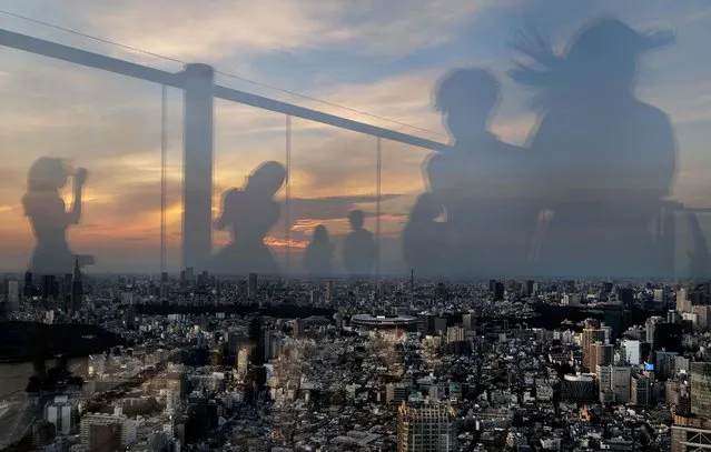 People are seen in a reflection as they enjoy the view at Shibuya Sky observation deck ahead of the official opening of the Tokyo 2020 Olympic Games, in Tokyo, Japan, July 21, 2021. (Photo by Kai Pfaffenbach/Reuters)
