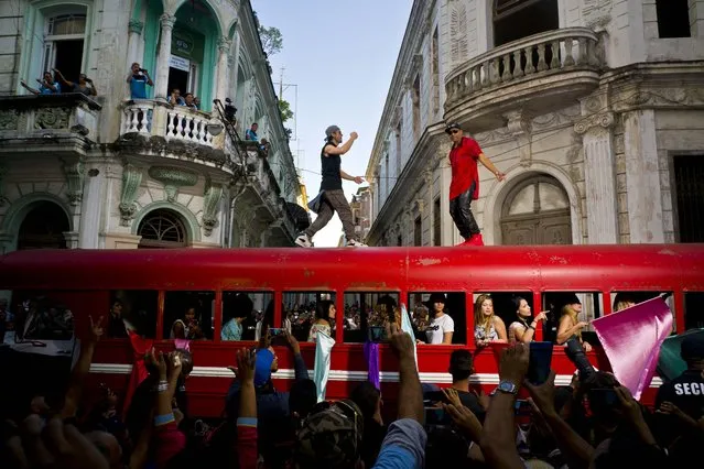 Singer Enrique Iglesias, center, and Cuban singer Descemer Bueno dance on top of a bus during the filming of their video in Old Havana, Cuba, Wednesday, January 11, 2017. Latin pop star Enrique Iglesias is in Cuba to film his latest music video for an upcoming single to be released later this year. (Photo by Ramon Espinosa/AP Photo)