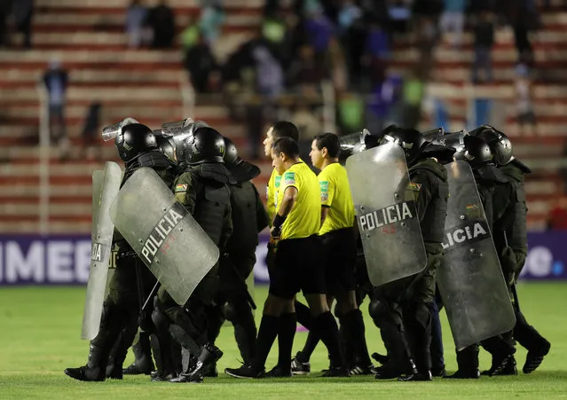Members of the police protect Peruvian referee Diego Haro and his line judges (in yellow) during the Copa Libertadores match between Bolivar and Defensor Sporting at the Hernando Siles stadium in La Paz, Bolivia, 23 January 2019. (Photo by Martin Alipaz/EPA/EFE)