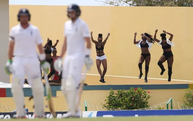 Cricket, West Indies v England, First Test; Sir Vivian Richards Stadium, Antigua, April 13, 2015: England's Joe Root and Ian Bell look on as girls dance in the background. (Photo by Jason O'Brien/Reuters)