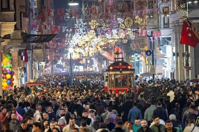 People walk past a historical tramway under Christmas light decorations on Istiklal street during preparations to celebrate the New Year 2024 in Istanbul on December 31, 2023. (Photo by Yasin Akgul/AFP Photo)