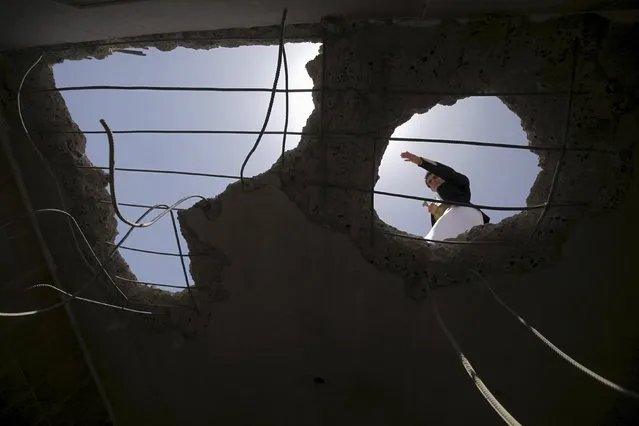 A man looks from a hole in the roof of his house at damage caused by an April 20 air strike that hit a nearby army weapons depot, in Sanaa April 21, 2015. (Photo by Mohamed al-Sayaghi/Reuters)