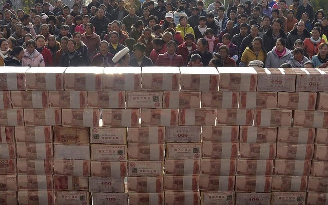 Villagers wait to collect their year-end bonus at Jianshe village, Liangshan, Sichuan province, China, Jan. 14, 2014. About 13,115,000 yuan ($2,169,221) were placed in the middle of a square before being distributed as bonus to around 340 villagers in return for their investment in the planting and breeding co-operative in the village in 2013. (Photo by Reuters/Stringer)