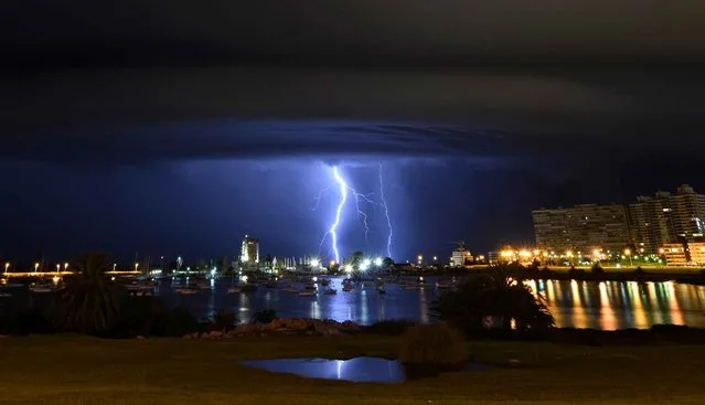 Lightning strikes behind the Port of Buceo during a thunderstorm in Montevideo, early on February 9, 2014. (Photo by Mariana Suarez/AFP Photo)