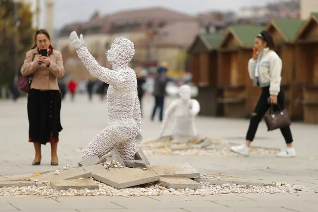 People walk between sculptures of an art installation created by Kosovar sculptor Eroll Murati titled “Find Me” is displayed for two weeks in the main square in Pristina, Kosovo, 09 November 2021. Sculptures of Eroll Murati symbolize the missing person's plea for their bodies to be found and urges institutions for greater efforts to find the remaining missing persons from the last war. Some 1,600 persons in Kosovo, most of them Albanians, are still listed as missing from the 1998-1999 war. (Photo by Valdrin Xhemaj/EPA/EFE)