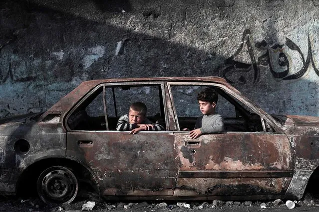 Children sit in a destroyed car in Rafah, on the southern Gaza Strip on February 28, 2024, amid ongoing battles between Israel and the Palestinian militant group Hamas. (Photo by AFP Photo)