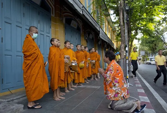 A Thai woman makes offerings to Buddhist monks who collect alms close to The Grand Palace in which King Maha Vajiralongkorn's coronation takes place on Sunday, May 5, 2019, in Bangkok, Thailand. Saturday began three days of elaborate centuries-old ceremonies for the formal coronation of Vajiralongkorn, who has been on the throne for more than two years following the death of his father, King Bhumibol Adulyadej, who died in October 2016 after seven decades on the throne. (Photo by Gemunu Amarasinghe/AP Photo)