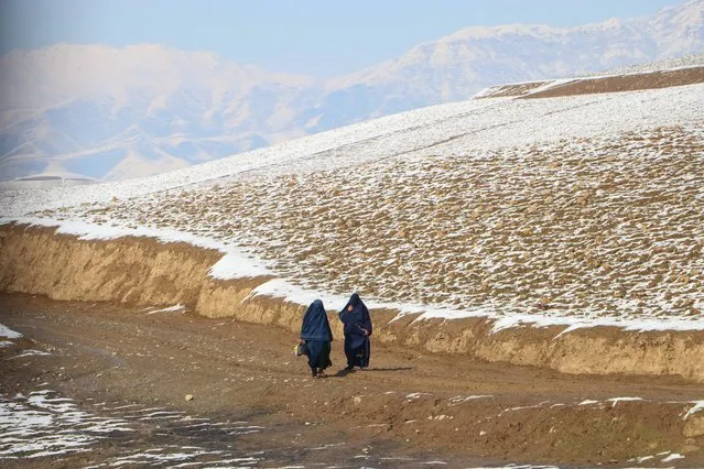 Afghan burqa-clad women walk down a hill road in Fayzabad on March 4, 2024. (Photo by Omer Abrar/AFP Photo)