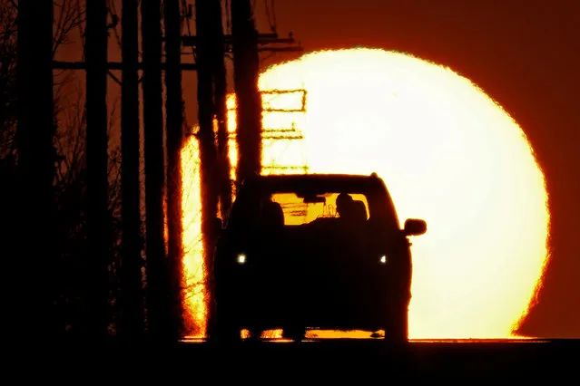 A motorist is silhouetted by the setting sun as they drive through an intersection on the first day of spring Tuesday, March 19, 2024, in Olathe, Kan. In the northern hemisphere, the vernal equinox marks the first day of spring when the sun appears to rise “due east” and set “due west” and day and night are nearly equal. (Photo by Charlie Riedel/AP Photo)