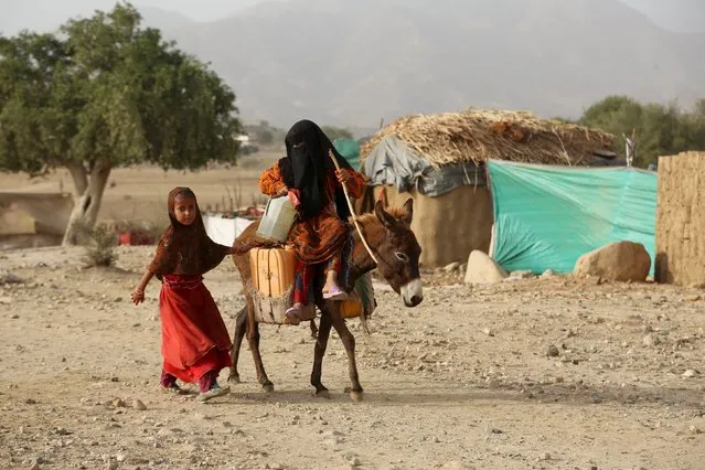 A girl rides a donkey as another walks by at the Shawqaba camp for internally displaced people who were forced to leave their villages by the war in Yemen's northwestern province of Hajjah March 12, 2016. In northwest Yemen, one of the poorest countries in the Middle East, about 400 families uprooted by the war have been stuck in the Shawqaba camp in Hajjah province for the past year. Residents live in poorly built huts that protect them neither from summer heat nor winter cold in a camp that lacks the most basic services. (Photo by Abduljabbar Zeyad/Reuters)