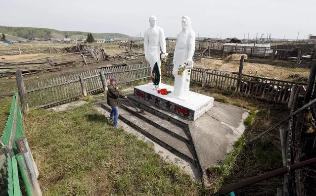 A woman cleans a World War Two monument to Red Army soldiers and to workers of the rear in the centre of Irkutskoye village, north of the Siberian city of Krasnoyarsk, Russia, May 18, 2015. Residents of the remote, sparsely inhabited village look after the monument, though the date and details of its creation are not known. (Photo by Ilya Naymushin/Reuters)