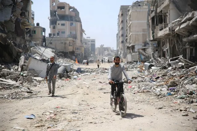 A man rides a bicycle near the debris of damaged building as the area around the Al-Shifa Hospital is destroyed in Gaza City, Gaza on April 01, 2024. The Israeli army said Monday that it wrapped up its military operation at the Al-Shifa Hospital complex in Gaza City, following a 14-day siege and incursion that resulted in scores of casualties and hundreds of arrests. (Photo by Omar El Qattaa/Anadolu via Getty Images)