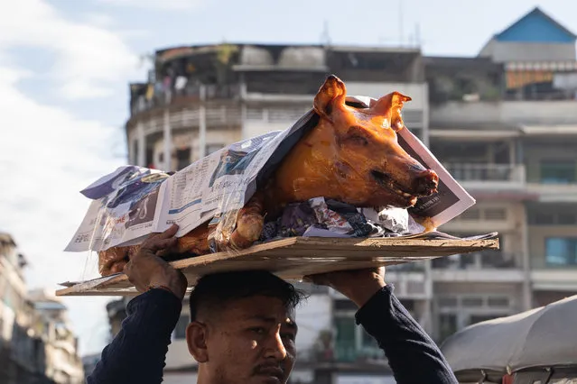 A person carries a roasted pig at a market ahead of Lunar New Year on January 21, 2023 in Phnom Penh, Cambodia. The Chinese diaspora of Southeast Asia is celebrating a lively Lunar New Year, as COVID-19 restrictions have been removed. It is traditionally a time for people to meet their relatives and take part in celebrations with families. In Cambodia, which has aligned it self closely with China and where China is investing heavily, celebration feasts feature suckling pigs, among other highlights. (Photo by Cindy Liu/Getty Images)