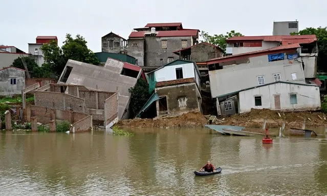A woman on a boat looks at damaged houses on the banks of Cau River in Vietnam's Bac Ninh province on April 8, 2024. (Photo by Nhac Nguyen/AFP Photo)