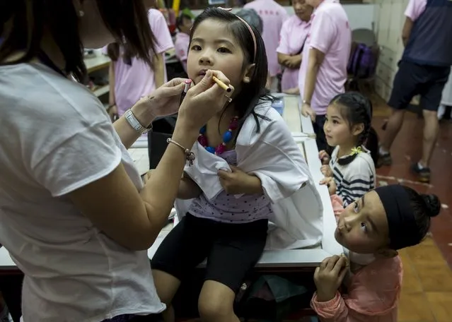 Phoebe Lo (L), a four-year-old, receives make up as Peony Chu (bottom R), a five-year-old, looks on before taking part in a Bun Festival parade at Hong Kong's Cheung Chau island, China May 25, 2015. (Photo by Tyrone Siu/Reuters)