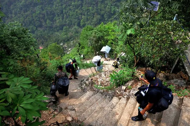 Porters and polling officers carry Voter Verifiable Paper Audit Trail (VVPAT) and Electronic Voting Machines (EVM) as they trek to reach a remote polling station, ahead of the first phase of the election, in Shillong, in the northeastern state of Meghalaya, India, on April 17, 2024. (Photo by Adnan Abidi/Reuters)