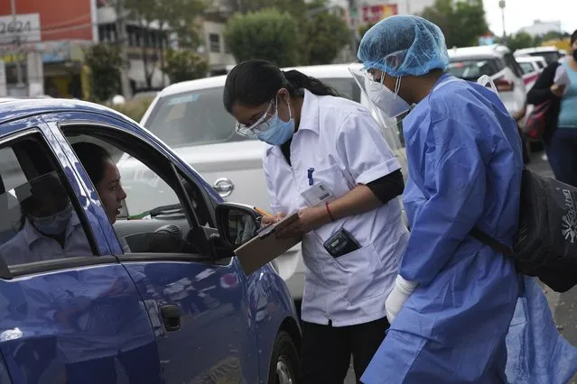 Pharmacy workers gather information as people line up in their cars for COVID-19 tests in Mexico City, Monday, January 10, 2022. (Photo by Marco Ugarte/AP Photo)