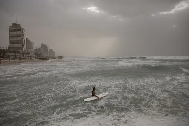 A surfer enters the Mediterranean Sea during stormy weather in Tel Aviv, Israel, Wednesday, December 8, 2021. (Photo by Oded Balilty/AP Photo)