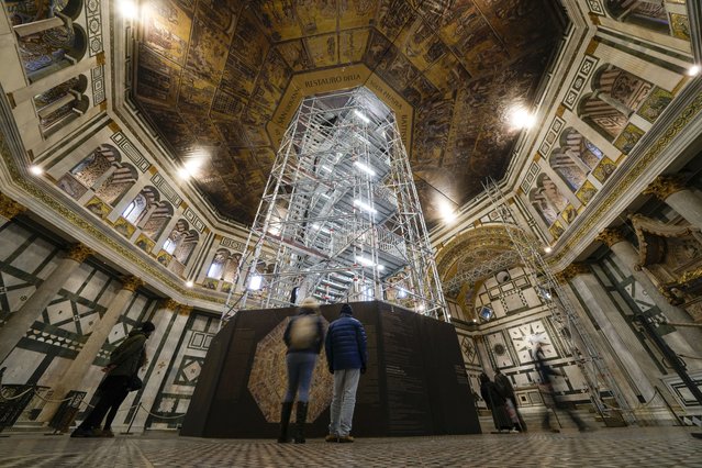 Visitors admire St. John's Baptistery, one of the oldest churches in Florence, central Italy, Tuesday, February 7, 2023. The Baptistery's dome is undergoing a restoration work that will be done from an innovative scaffolding shaped like a giant mushroom that will stand for the next six years in the center of the church, and that will be open to visitors allowing them for the first and perhaps only time, to come come face to face with more than 1,000 square meters of precious mosaics covering the dome. (Photo by Andrew Medichini/AP Photo)