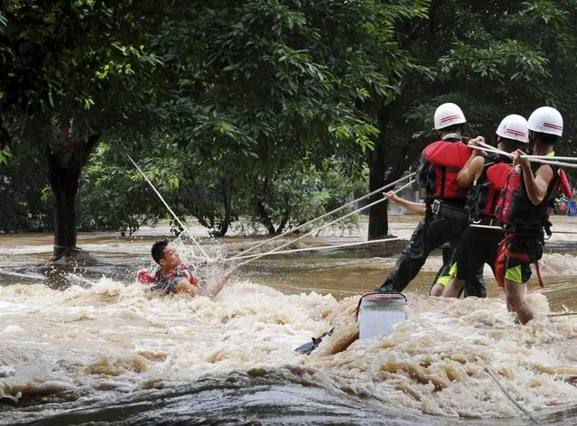 Rescue workers pull a man trapped by a sudden rise of water level during a heavy rainfall in the Lijiang River, Guilin, Guangxi Zhuang Autonomous Region, July 2, 2015. (Photo by Reuters/Stringer)