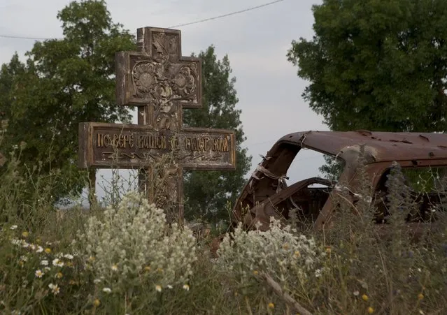 An abandoned car is seen near a cross in the village of Tbeti near Tskhinvali, the capital of the breakaway region of South Ossetia, Georgia, July 4, 2015. (Photo by Kazbek Basaev/Reuters)