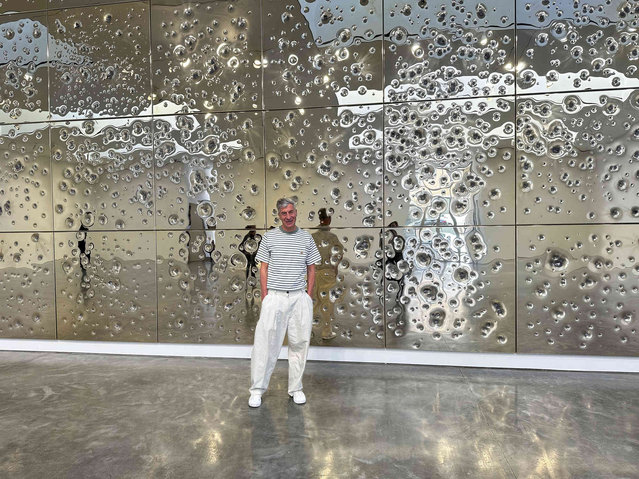 Italian artist Maurizio Cattelan poses with his installation, “Sunday”, at Gagosian gallery on May 1, 2024, in New York. The installation consists of 64 panels plated with 24-karat gold and pockmarked by gunfire. (Photo by Jocelyn Noveck/AP Photo)