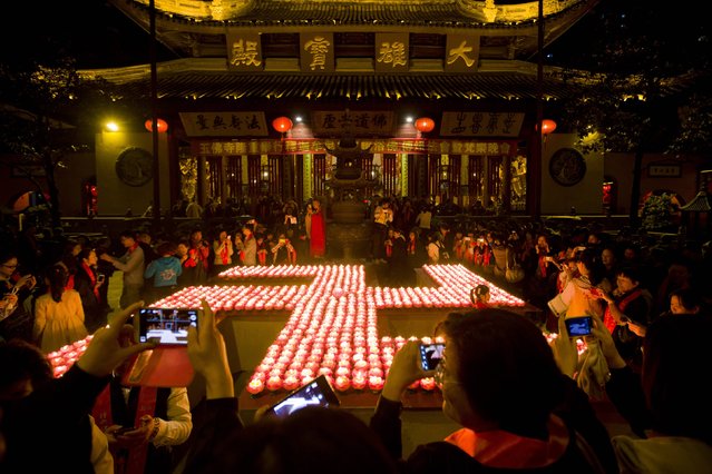 Buddhists place lotus-shaped candle holders to form the shape of a swastika, an auspicious symbol, during a ceremony to celebrate Buddha's birthday at the Yufo Temple in Shanghai May 6, 2014. (Photo by Aly Song/Reuters)