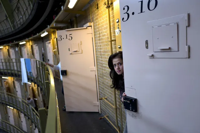 In this Saturday, May 7, 2016 photo, Afghan refugee Shazia Lutfi, 19, peeks through the door of her room at the former prison of De Koepel in Haarlem, Netherlands. The government has let Belgium and Norway put prisoners in its empty cells and now, amid the huge flow of migrants into Europe, several Dutch prisons have been temporarily pressed into service as asylum seeker centers. (Photo by Muhammed Muheisen/AP Photo)