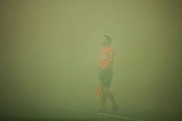 A referee stands on the pitch blanketed in green smoke caused by smoke bombs lobbed by fans at the start of the French L1 football match between Girondins de Bordeaux and Montpellier Herault SC at the Matmut Atlantique Stadium in Bordeaux, western France on March 20, 2022. (Photo by Thibaud Moritz/AFP Photo)