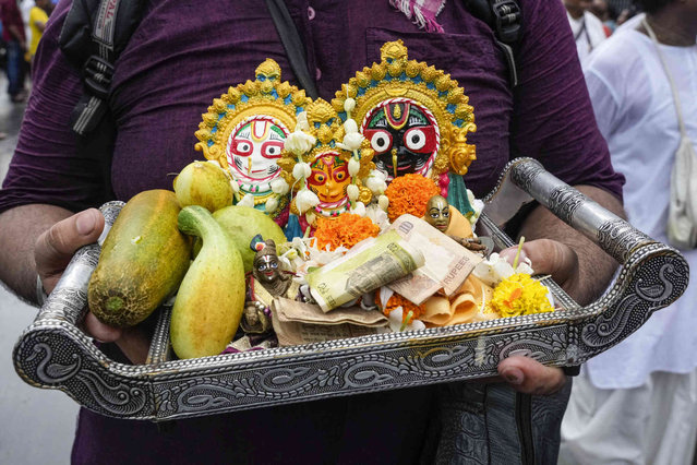 Hindu devotees participate carrying the deities of Jagannath, Balaram and Subhadra during the annual Ratha Yatra or chariot festival in Kolkata, India, Sunday, July 7, 2024. The annual procession of the three idols of Hindu deities Lord Jagannath, Balabhadra and Subhadra is taken out in a grand procession in specially made chariots called raths, which are pulled by thousands of devotees. (Photo by Bikas Das/AP Photo)