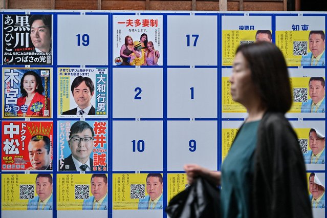 A woman walks past an election poster board displaying various candidates in the upcoming July 7 Tokyo gubernatorial election, along a street in Tokyo on June 23, 2024. (Photo by Richard A. Brooks/AFP Photo)