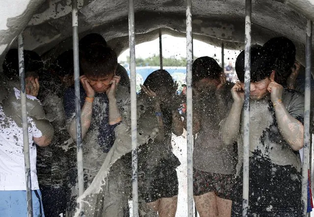 Tourists takes a mud shower during the Boryeong Mud Festival at Daecheon beach in Boryeong, South Korea, July 18, 2015. About 2 to 3 million domestic and international tourists visit the beach during the annual mud festival, according to the festival organisers. (Photo by Kim Hong-Ji/Reuters)