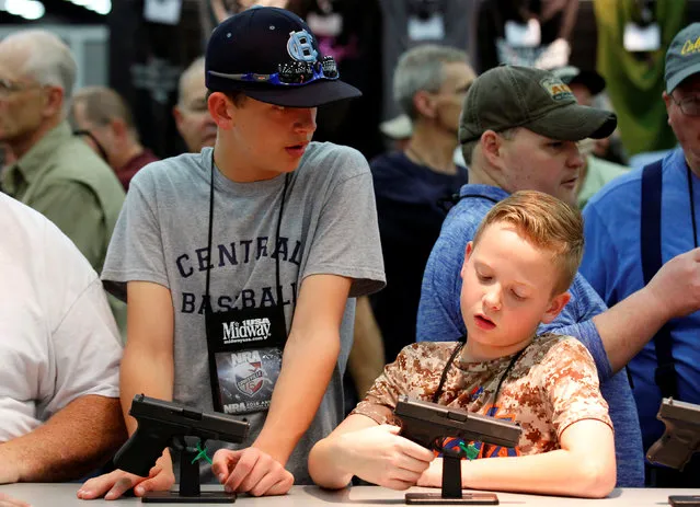 Gun enthusiasts look over guns at FN America firearms at the National Rifle Association's annual meetings and exhibits show in Louisville, Kentucky, May 21, 2016. (Photo by John Sommers II/Reuters)