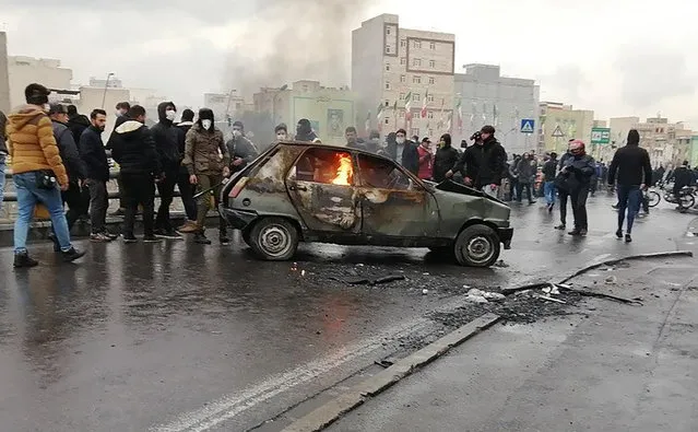 Iranian protesters gather around a burning car during a demonstration against an increase in gasoline prices in the capital Tehran, on November 16, 2019. One person was killed and others injured in protests across Iran, hours after a surprise decision to increase petrol prices by 50 percent for the first 60 litres and 300 percent for anything above that each month, and impose rationing. Authorities said the move was aimed at helping needy citizens, and expected to generate 300 trillion rials ($2.55 billion) per annum. (Photo by AFP Photo/Stringer)