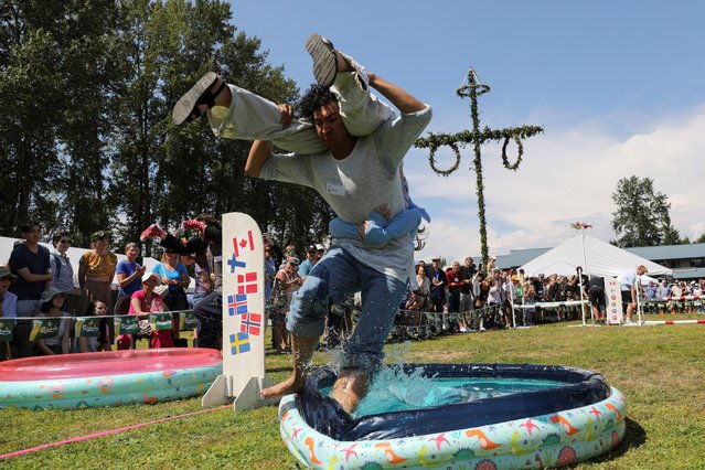 Competitors take part in the wife-carrying contest during the Scandinavian Midsummer Festival in Burnaby, Canada on June 25, 2023. (Photo by Chris Helgren/Reuters)