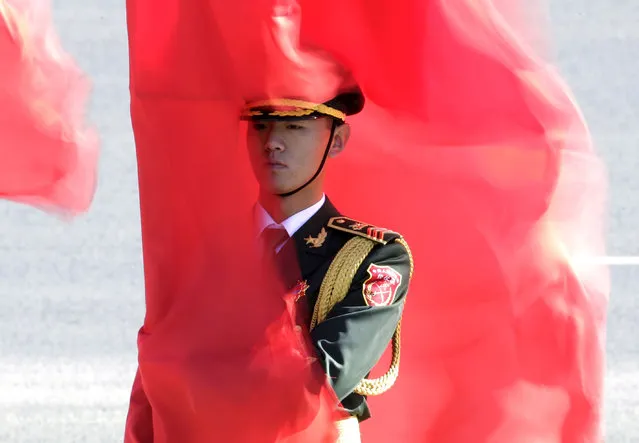 A soldier from the honour guards holding a red flag stands during a welcoming ceremony for Germany's Chancellor Angela Merkel outside the Great Hall of the People in Beijing, China, October 29, 2015. (Photo by Jason Lee/Reuters)