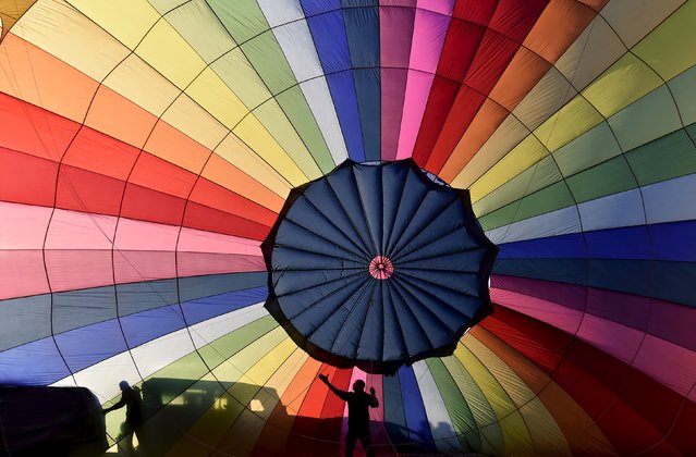 Crew members inflate a balloon during a mass launch at the Bristol International Balloon Fiesta in south west England August 7, 2015. (Photo by Toby Melville/Reuters)