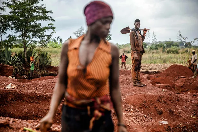 A gold miner observes from the distance how some women miners work at an open-pit gold mine in Nyarugusu, Geita Region, Tanzania on May 27, 2022. Tanzania is a land rich in minerals and one of the main gold producers in Africa, with gold representing more than 90% of the country's mineral exports. Artisanal and small-scale gold mining have culturally and historically relegated women's participation. The extractive sector in Tanzania has historically been a male-dominated industry with high levels of harassment, sеxual abuse, discrimination and misconceptions over women's involvement, and contributions following traditional beliefs. (Photo by Luis Tato/AFP Photo)