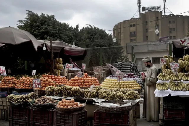 In this Tuesday, February 14, 2017 photo, a fruit vendor checks an apple as he waits for customers in the Sayeda Zeinab neighborhood of Cairo, Egypt. (Photo by Nariman El-Mofty/AP Photo)