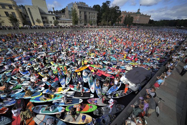 People wait at the mass start on their stand-up paddle (SUP) boards in the Fontanka River during the annual costumed 'Fontanka' SUP-boards festival in St. Petersburg, Russia, Saturday, August 5, 2023. (Photo by Dmitri Lovetsky/AP Photo)