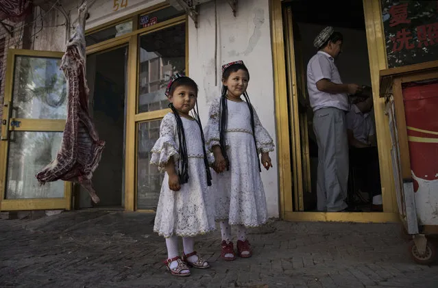 Ethnic Uyghur girls wear traditional clothing as they stand outside a butcher shop on June 29, 2017 in the old town of Kashgar, in the far western Xinjiang province, China. (Photo by Kevin Frayer/Getty Images)
