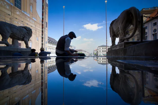 The Theatiner cathedral, the Ludwig street, the blue sky and the Munich Residence are reflected in a puddle on the ground of the Feldherrn hall in Munich, Germany, May 18, 2015. (Photo by Peter Kneffel/EPA)