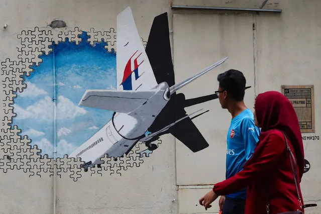 A couple look at a Malaysia Airlines flight MH370 mural painting at Shah Alam, outside Kuala Lumpur, Malaysia, 07 March 2019. Malaysia Airlines flight MH370 went missing on its way from Kuala Lumpur to Beijing with the loss of all 239 people on board, on 08 March 2014. (Photo by Fazry Ismail/EPA/EFE)