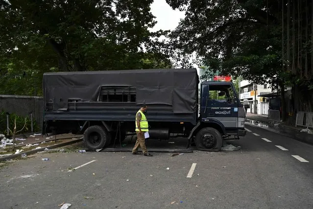 A member of security personnel inspects a police vehicle, a day after it was vandalised by the protestors in front of the residence of Sri Lanka's Prime Minister, in Colombo on July 10, 2022. Sri Lankan protesters set the prime minister's private home on fire, hours after chasing the president from his residence, as months of frustration over an unprecedented economic crisis boiled over on July 9. (Photo by Arun Sankar/AFP Photo)