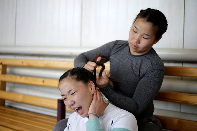 Mongolia's wrestler Oyuntuya Otgonbat reacts as her teammate Sarankhuhuo Erdenetuya ties her hair before a daily training session at the Mongolia Women’s National Wrestling Team training centre in Bayanzurkh district of Ulaanbaatar, Mongolia, July 1, 2016. (Photo by Jason Lee/Reuters)