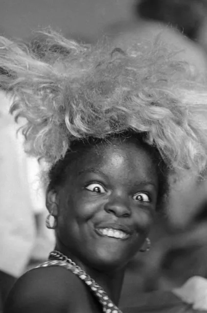 This young Miss takes time out for a bit of comedy as she tries on a blond wig she found in Salvation Army clothing center for hurricane Camille refugees at Gulfport, Miss., on August 25, 1969. (Photo by Joe Holloway/AP Photo)