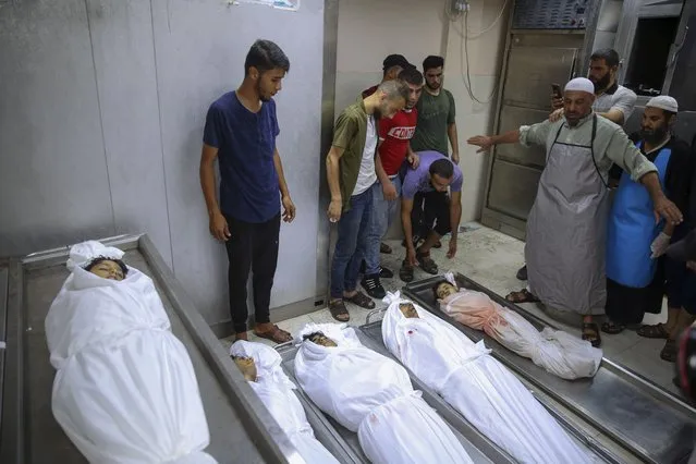 Mourners pray over the bodies of six Palestinians including children killed in an explosion in Jebaliya refugee camp, at the hospital morgue in Jebaliya, northern Gaza Strip, Saturday, August 6, 2022. On Saturday, a projectile hit in Jebaliya, killing the six. Palestinians held Israel responsible, while Israel said it was investigating whether the area was hit by an errant rocket. (Photo by Abdel Kareem Hana/AP Photo)